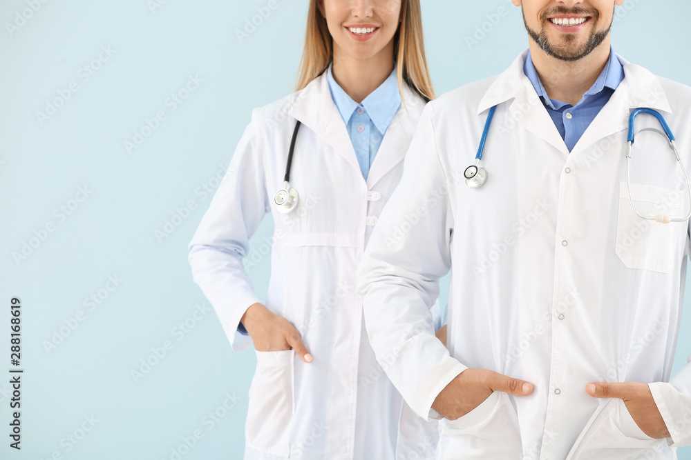 Male and female doctors on light color background