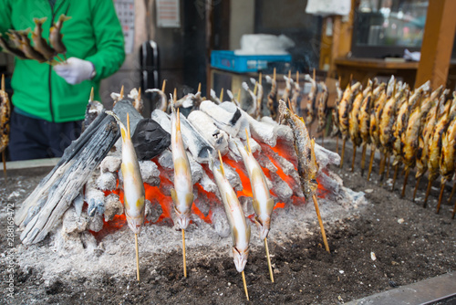 NIKKO, JAPAN - NOVEMBER 08, 2018:Charcoal grilled Ayu fish with salt. Traditional Japanese street food at Kegon waterfall in Nikko, Japan. photo