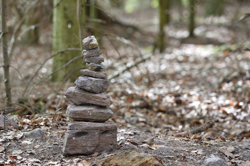 A small pyramid of stones made by tourists in the forest Schwarzwald on the background of trees