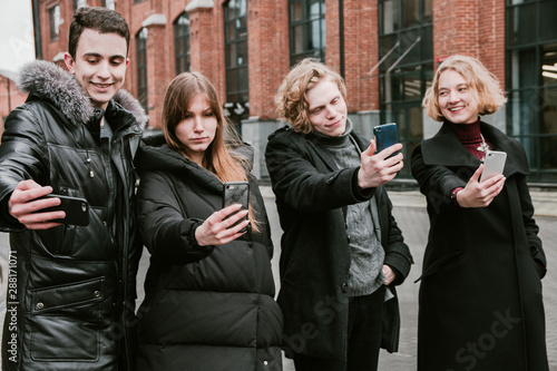 Friendly company of young people having fun and taking selfies