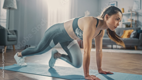 Profile Shot of a Beautiful Confident Strong Fitness Female in a Grey Athletic Outfit Doing Mountain Climber Exercises in Her Bright and Spacious Apartment with Cozy Minimalistic Interior.