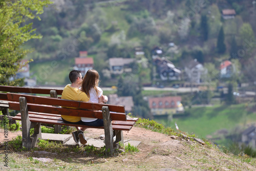 Bad Wildbad, Germany - April 22, 2019: A guy and a girl are sitting on a bench and admiring, the beautiful European landscape. Romantic meeting of a guy and a girl on top of a mountain
