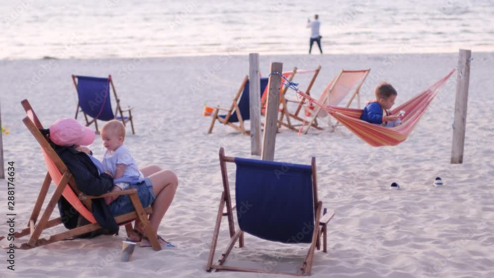 Evening baltic sea nature family mother with children in hammock and chair on sand beach relaxing Evening baltic sea nature family mother with children in hammock and chair on sand beach relaxing