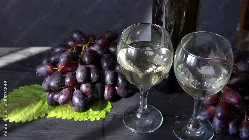 Black grapes, a glass of white wine and a bottle of wine on dark table Video HD Black grapes, a glass of white wine and a bottle of wine on dark table Video HD