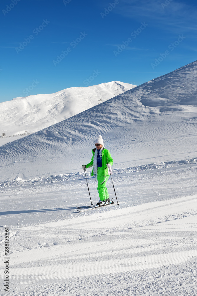 Skier on snowy ski slope at nice sun day