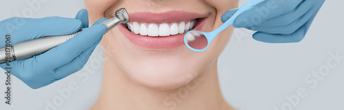 Cropped perfect smile and dentist hands holding a dental drill and an angle mirror. Dentistry and teeth treatment