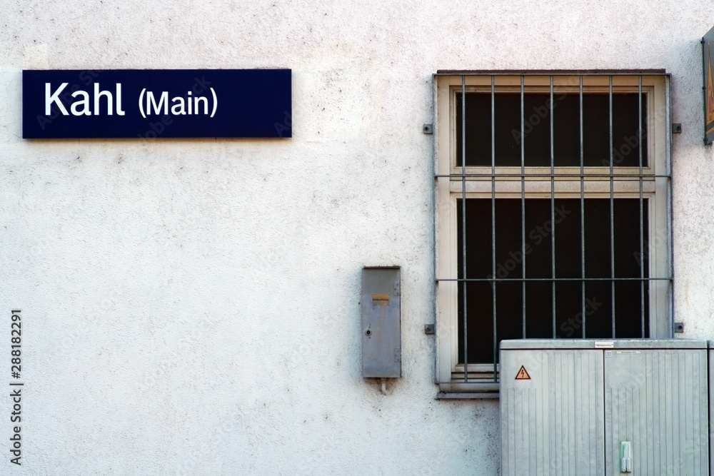 Die Wand des Bahnhofsgebäudes der Stadt Kahl mit einem Schild und vergittertem Fenster. .. Die Wand des Bahnhofsgebäudes der Stadt Kahl mit einem Schild und vergittertem Fenster. ..