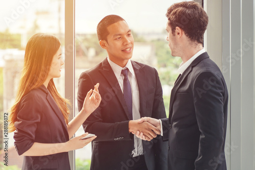 Two businessmen shaking hands with a woman translator standing on the side. photo