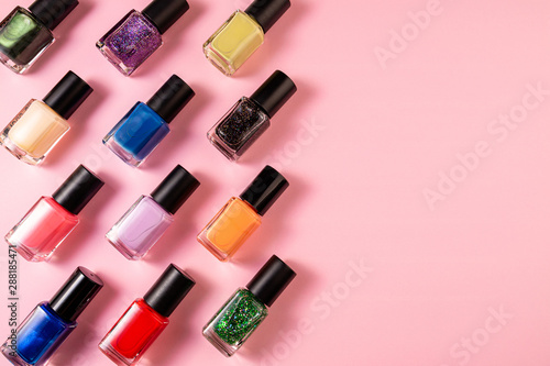 Set of various nail polish bottle on pink background with copy space. Stylish trendy nail polish for female manicure. Colorful nail lacquer top view