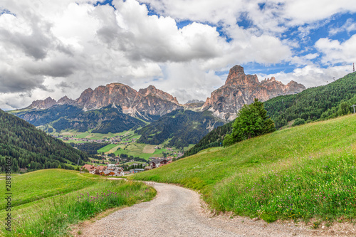 Picturesque alpine road leading to the city Corvara in Badia and Italian Dolomites with a peak Sassongher in the background.