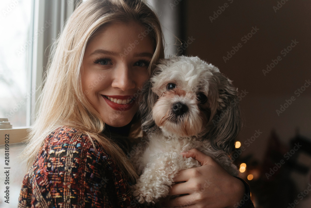 A woman in her twenties celebrating christmas with her small dog at home A woman in her twenties celebrating christmas with her small dog at home