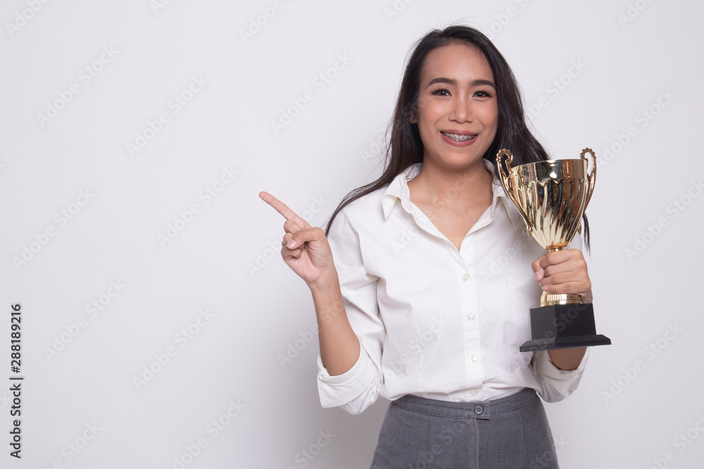 Obraz premium Successful young asian woman holding a trophy point to blank space.