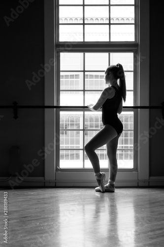 Black & white silhouette of dancer looking out of a downtown window.