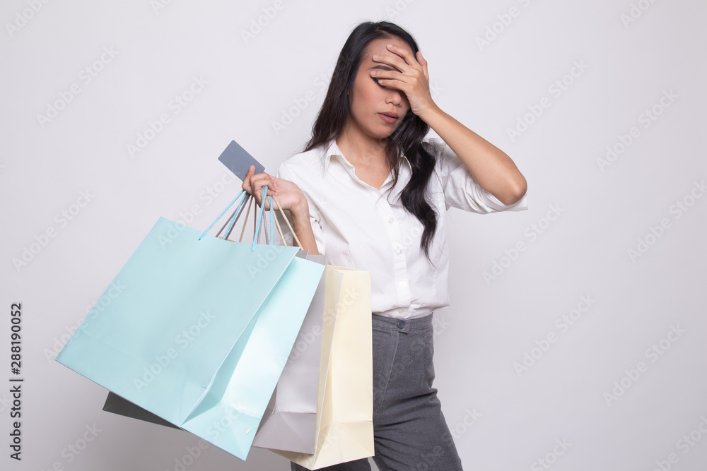 Unhappy young Asian woman with shopping bags and credit card. Unhappy young Asian woman with shopping bags and credit card.