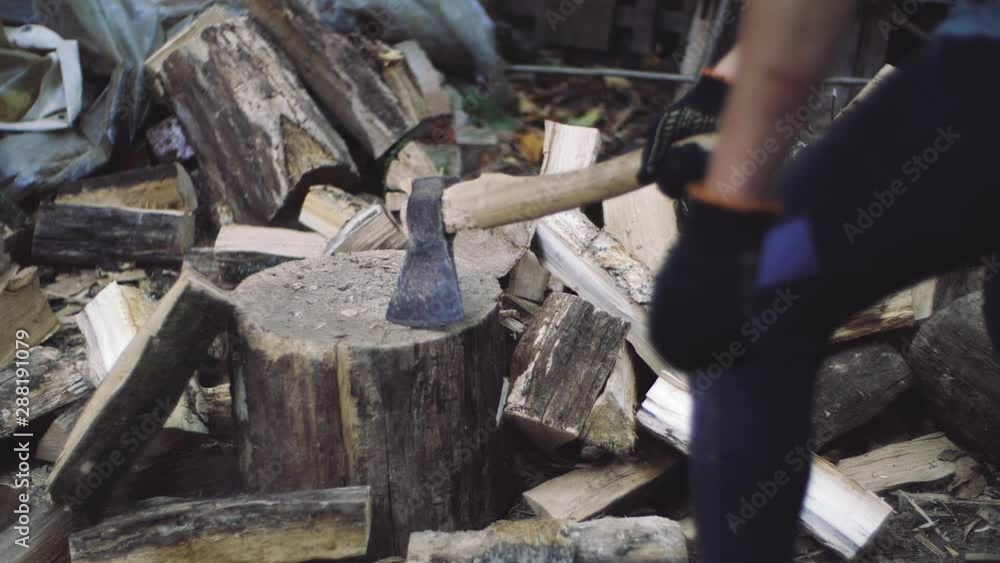 Man chops wood outdoors in slow motion. Man's hands working with ax. A man woodcutter chops tree trunks with an ax for firewood. Man chops wood outdoors in slow motion. Man's hands working with ax. A man woodcutter chops tree trunks with an ax for firewood.