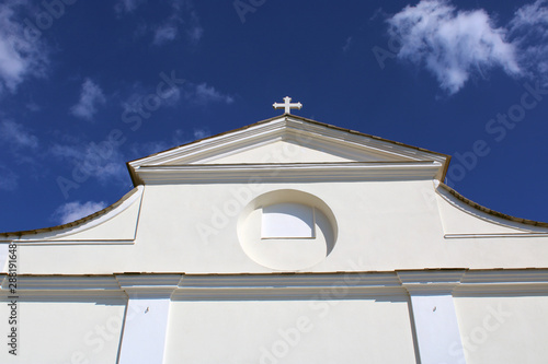 Facciata di chiesa con croce svettante nel cielo azzurro photo