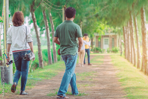 Couple walking and taking photos under the pine trees in the public park.