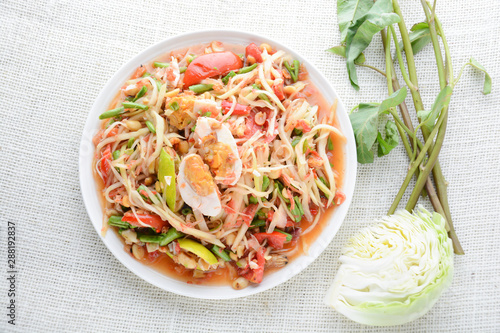 Papaya Salad with Satled Eggs, Pound chilies and garlic then place sliced tomato, eggplant and salted egg. Add fish sauce, lemon, sugar, chopped papaya then mixed all the ingredients together. photo