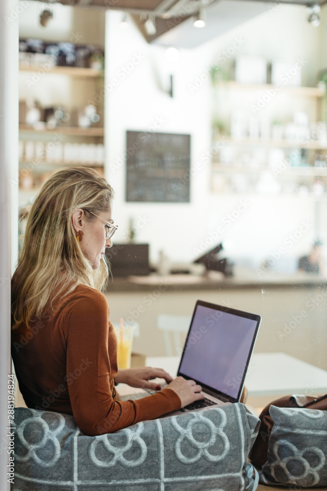 Woman with autumn outfit working inside coffee bar.