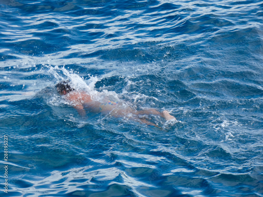 Nadador con boya protectora, haciendo deporte de natación, nadando en el mar mediterráneo