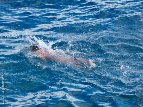 Nadador con boya protectora, haciendo deporte de natación, nadando en el mar mediterráneo