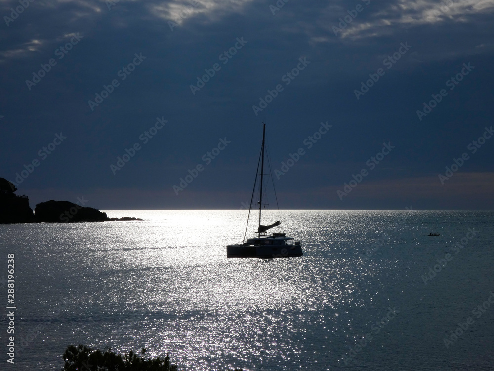 Barco velero anclado en el reflejo del sol en medio de una Bahía