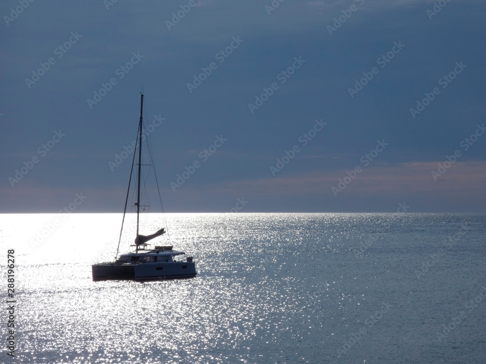 Barco velero anclado en el reflejo del sol en medio de una Bahía