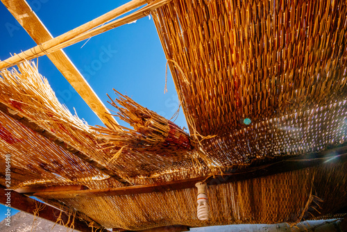 Canvas-taulu The hole in the straw roof and the view of the blue sky on the tourist stop near bedouin settlement near Dahab, Egypt