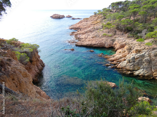 Paisaje de la Costa Brava catalana, España, con el mar azul, islas, aguas cristalinas, árboles y acantilados