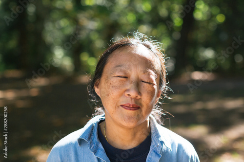 Mature asian woman practicing tai chi outside.