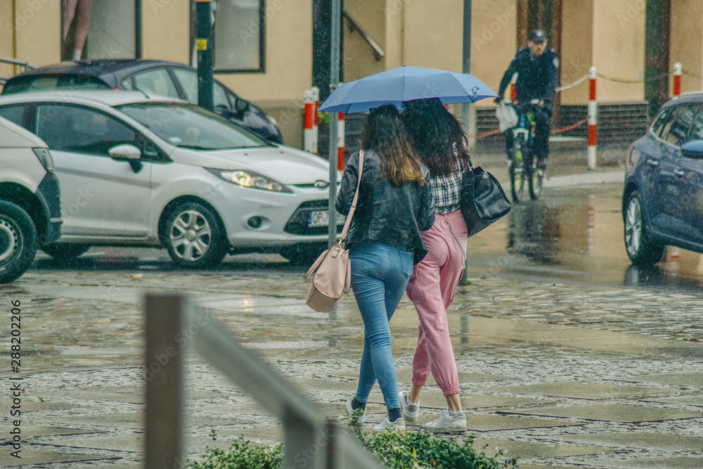 para kobiet idzie pod parasolem chroniąc się przed deszczem
