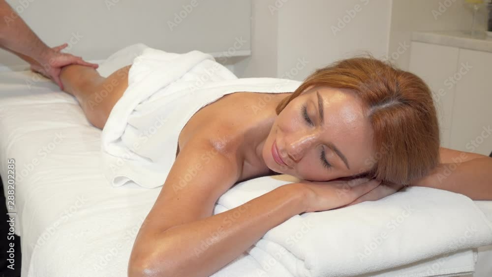 Beautiful woman getting full body massage at spa center. Professional masseur doing slimming anti-cellulite massage on the leg of a female client. Beauty, pampering concept Beautiful woman getting full body massage at spa center. Professional masseur doing slimming anti-cellulite massage on the leg of a female client. Beauty, pampering concept