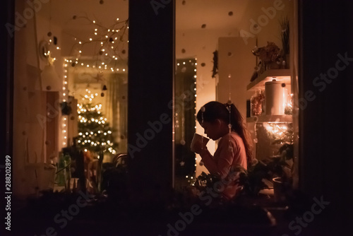 Wallpaper Mural Young girl sipping hot chocolate in the kitchen seen from outside through a window. Torontodigital.ca