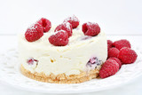 Mini cheesecake with white chocolate and raspberries on a white wooden background