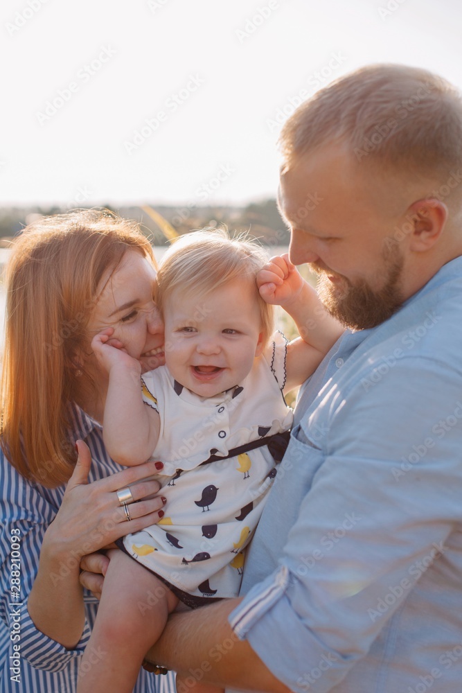 Happy young family with baby-daughter having fun in backlit