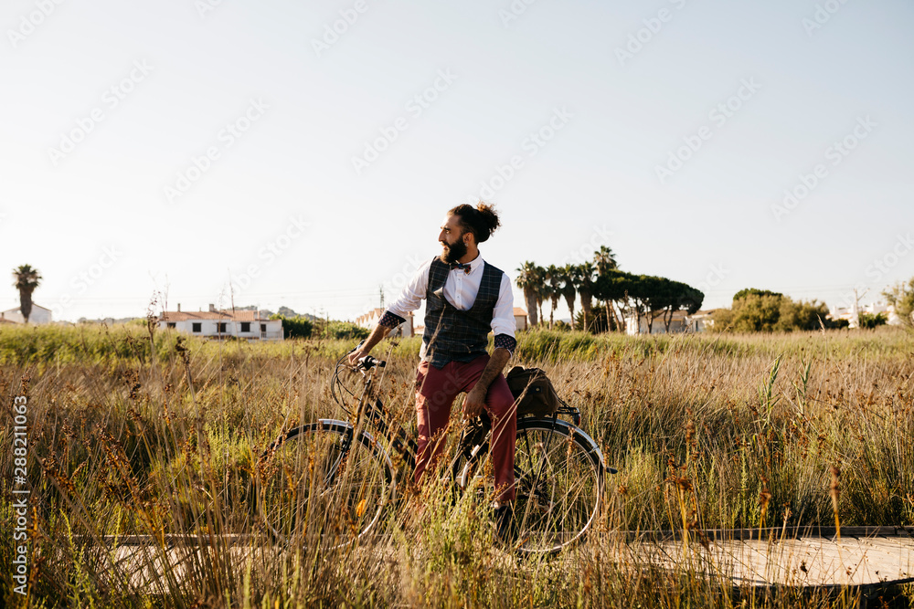 Well dressed man with his bike on a wooden walkway in the countryside having a break Well dressed man with his bike on a wooden walkway in the countryside having a break