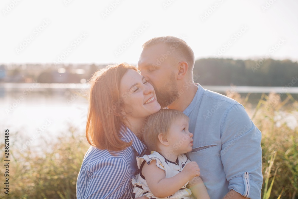 Happy family with baby girl kissing and embracing outdoors Happy family with baby girl kissing and embracing outdoors