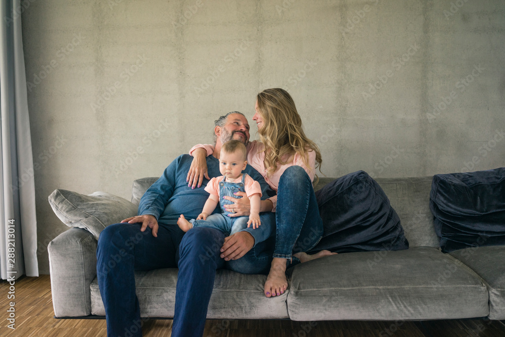 Happy family of three sitting on couch at home Happy family of three sitting on couch at home
