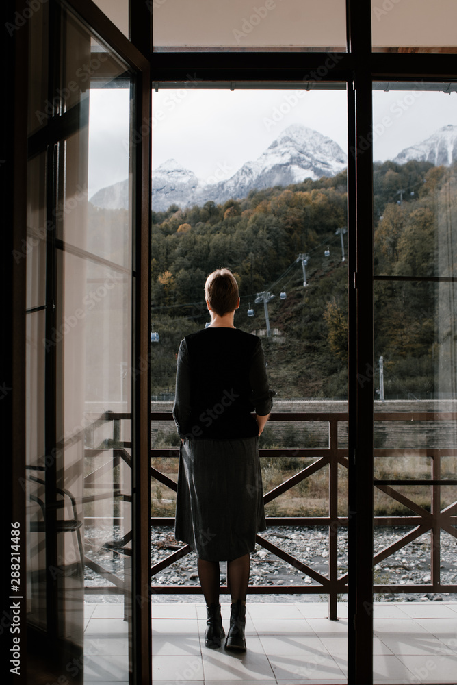 Woman?standing on balcony against mountains Woman?standing on balcony against mountains