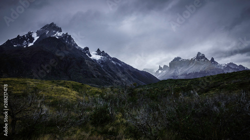 Torres del Paine trail. On the right is the ‘Paine Grande’ mountain. Below, you can see many wild vegetation an snowy peaks. Patagonia, Chile