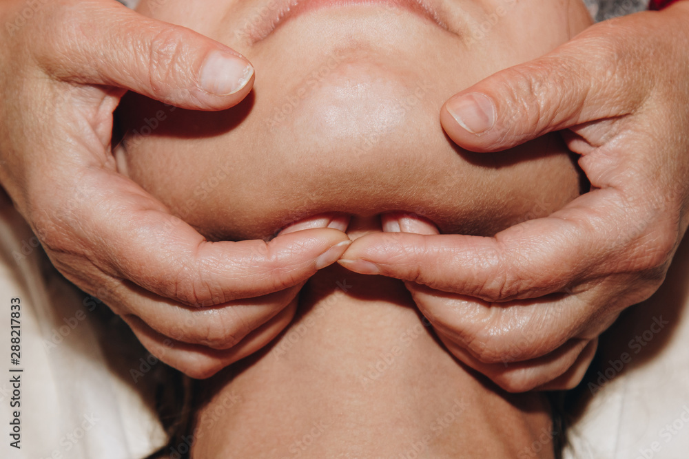 Fototapeta premium spa specialist is doing facial massage to a young girl in a medical cap. beauty treatments close-up