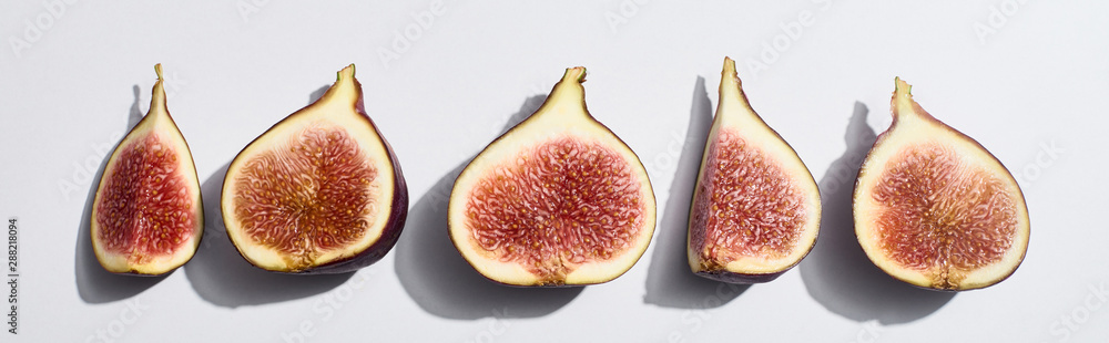 panoramic shot of ripe cut delicious figs in row on white background panoramic shot of ripe cut delicious figs in row on white background