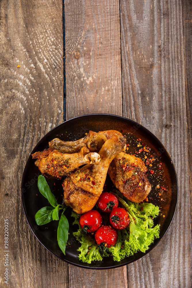 Fried chicken drumsticks with vegetables on wooden table Fried chicken drumsticks with vegetables on wooden table