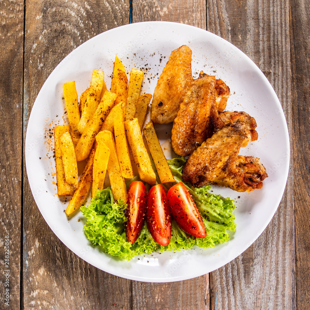 Grilled chicken wings, chips and vegetables Grilled chicken wings, chips and vegetables
