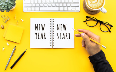 New year new start text with youngman writing on notepad on color desk table.Business goal-plan-action and resolution concepts