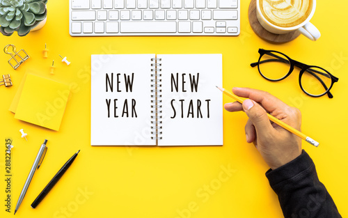 New year new start text with youngman writing on notepad on color desk table.Business goal-plan-action and resolution concepts photo