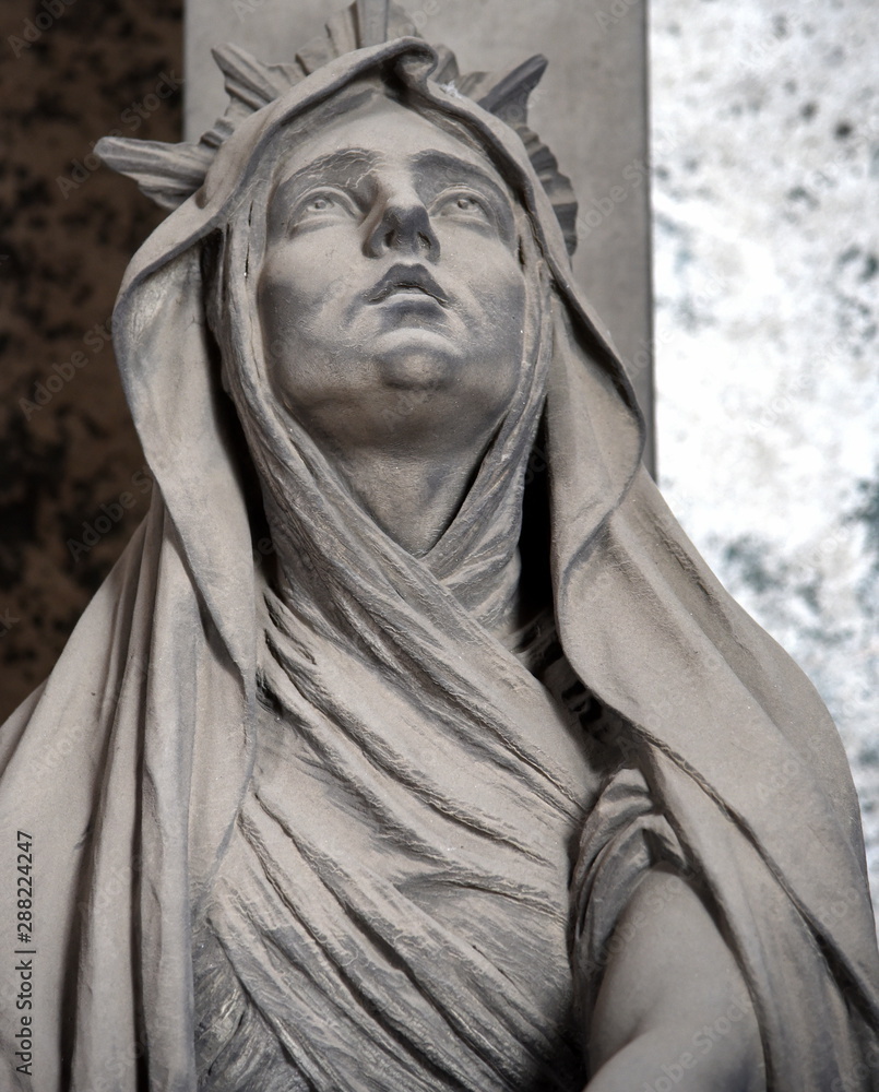 Skulptur einer zum Himmel schauenden Frau auf einem Friedhof Skulptur einer zum Himmel schauenden Frau auf einem Friedhof