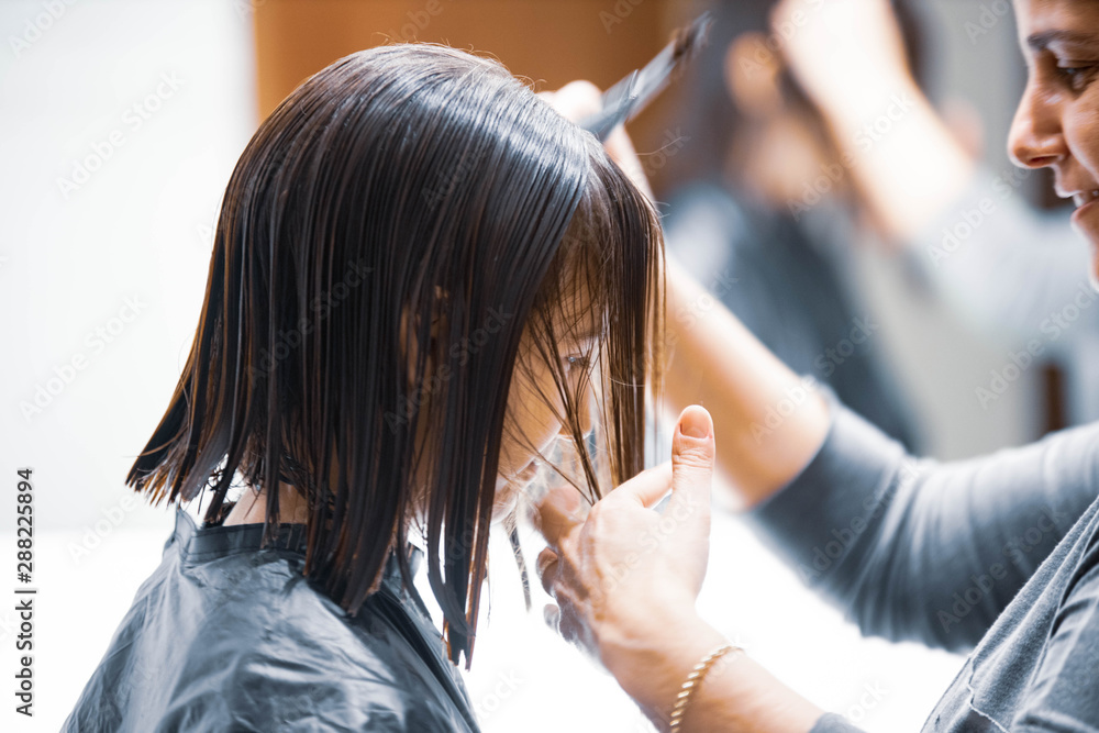 Fototapeta premium Madre cortando el cabello a su hija en casa