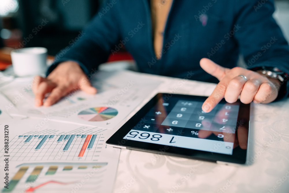 Close-up Of A Businessperson's Hand Analyzing Bill On Digital Tablet Over Desk. Close-up Of A Businessperson's Hand Analyzing Bill On Digital Tablet Over Desk.