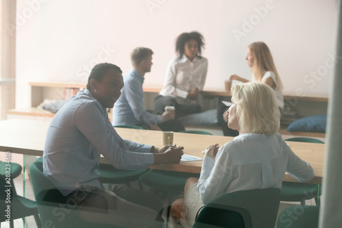 Diverse employee talk discussing ideas at break in boardroom